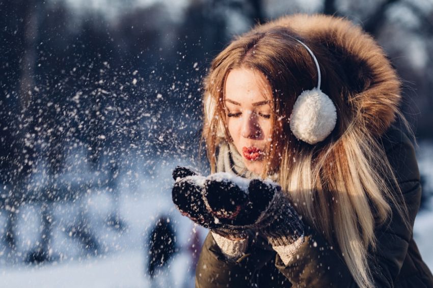 Winter Fashion - woman blowing snow on her hands